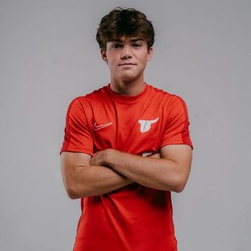 Young man in a red sports jersey with arms crossed.