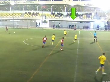 Youth soccer match in progress on an artificial turf field with spectators in stands.
