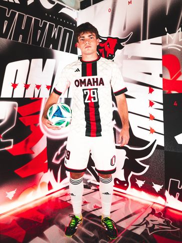 Soccer player in Omaha uniform holding a ball, standing confidently.