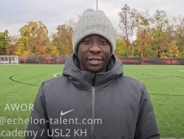 Man in winter hat and jacket on soccer field during autumn.