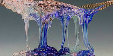 Close-up of blue and clear viscous liquid dripping from a surface.