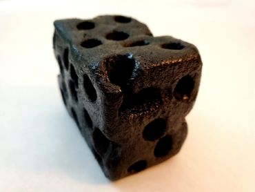 A black, porous, irregularly shaped object with multiple holes.