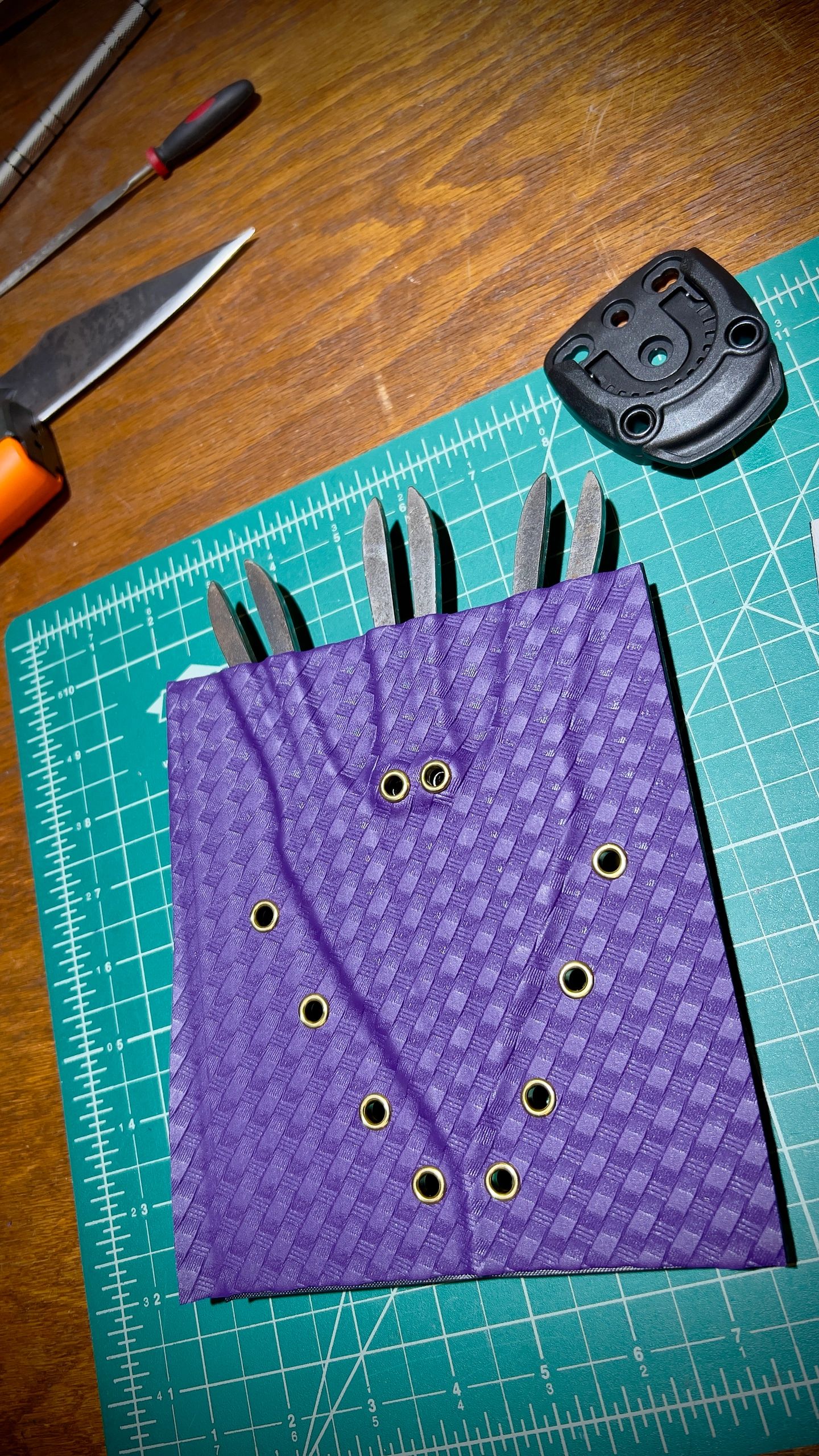 Custom sheath that holds three squid shaped implements, purple and black with gold accents