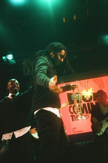 Musicians performing on stage with vibrant lighting and a trumpet in hand.