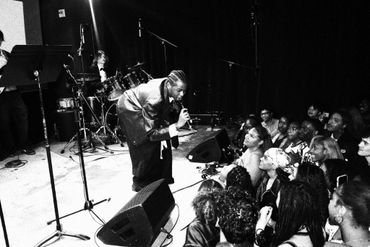 Black-and-white photo of a singer engaging with an enthusiastic crowd at a live music performance.