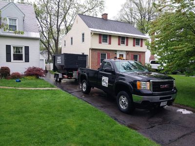 Black GMC pickup truck towing a trailer in a suburban driveway.