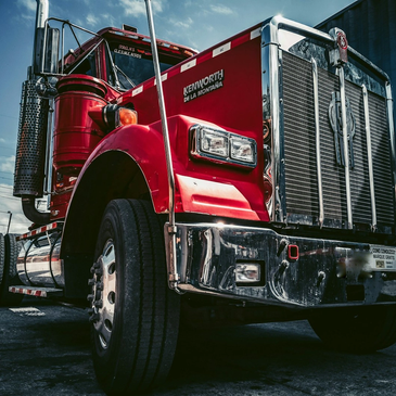 Red Kenworth semi-truck from a low angle.