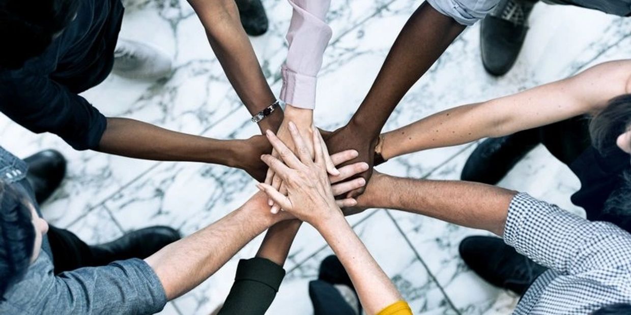 Diverse group joining hands in unity over a marble floor.