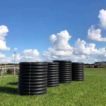 Three large black coils on grass under a blue sky.