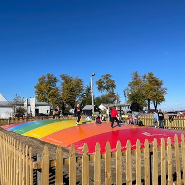 Kids playing on a colorful outdoor inflated bouncing pad.