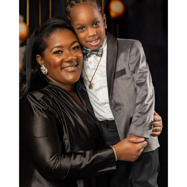 A woman and young boy dressed elegantly, smiling warmly while embracing.