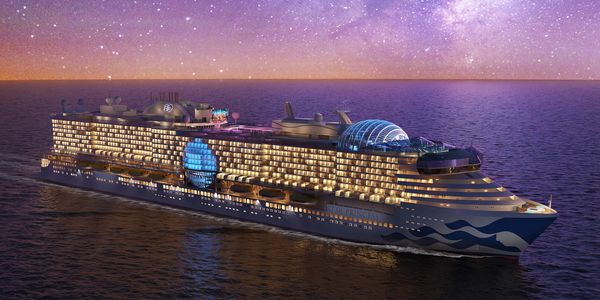 A luxurious cruise ship illuminated under a starry night sky at sea.