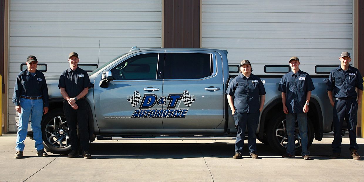 Five men stand by a D&amp;T Automotive truck.