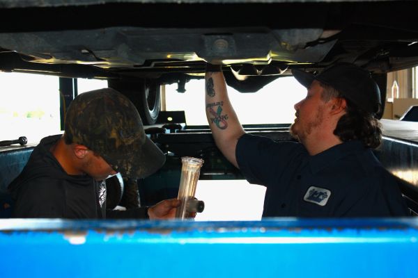 Two mechanics working under a vehicle.