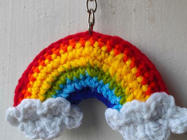 Crocheted rainbow keychain with clouds on a white background.