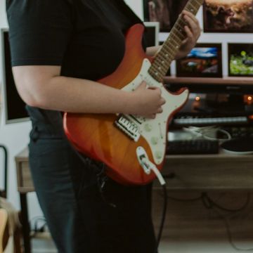 A woman playing electric guitar advertising beginner guitar lessons.