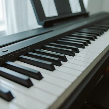 Close-up of a modern digital piano keyboard with black and white keys advertising piano lessons.