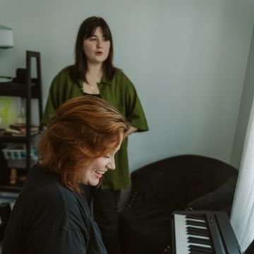 A joyful person plays the piano 
(scales) while adult student sings vocal exercises.