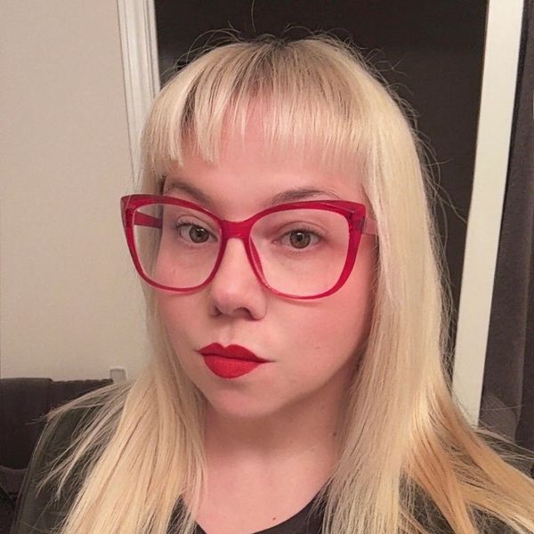 Woman with blonde hair, red glasses, and red lipstick.