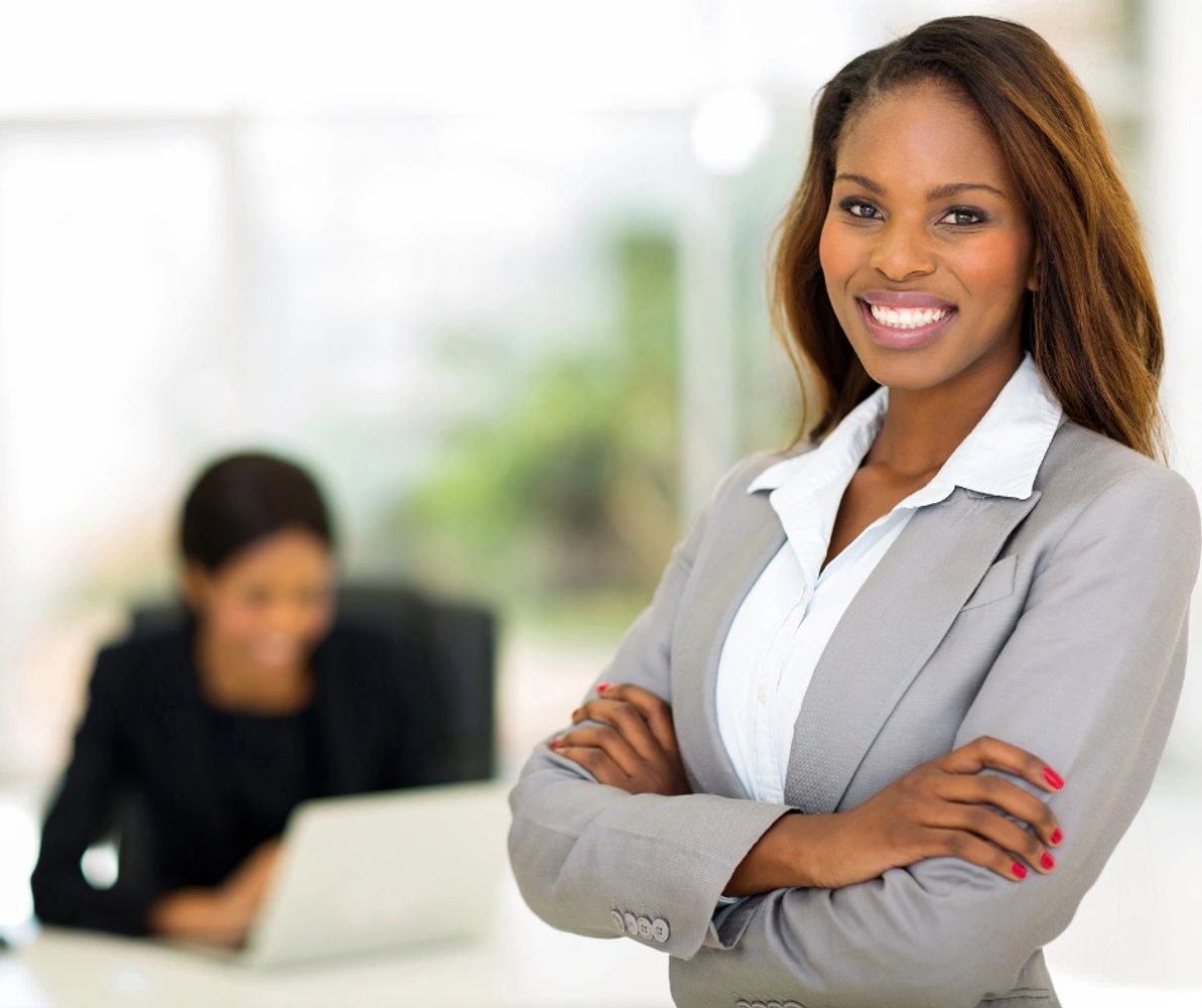Lady wearing a professional business suit with arms folded and smiling.