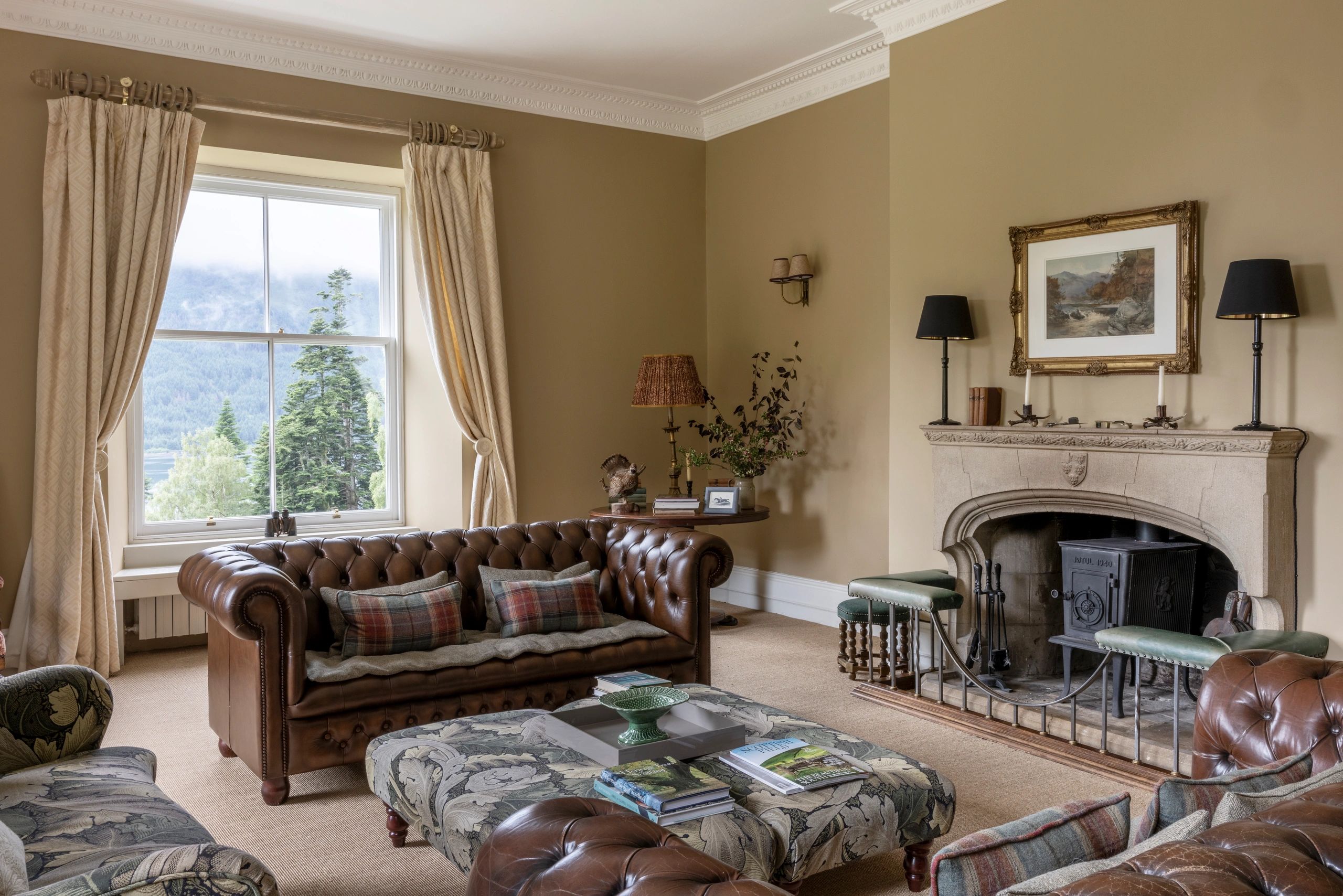 Cozy living room with leather sofas, a fireplace, and scenic window view.