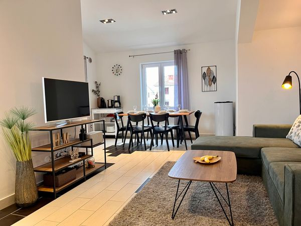 Modern living and dining area with cozy sofa, wooden table, and minimalist decor.