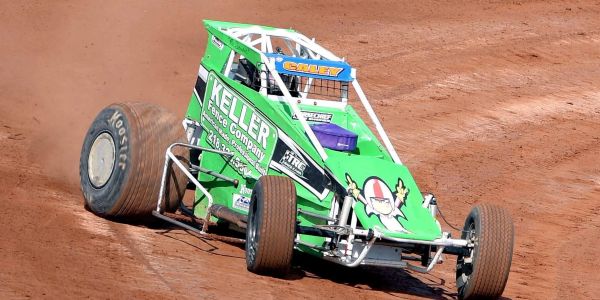 Green sprint car racing on dirt track.