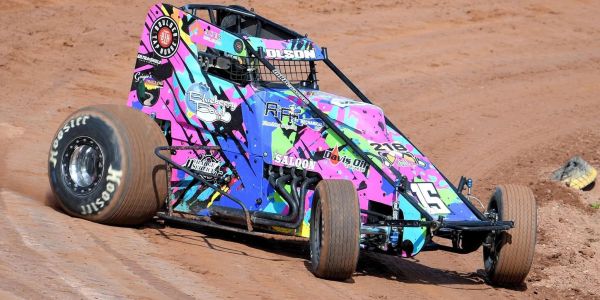 Colorful sprint car racing on dirt track.