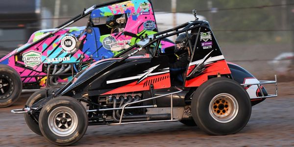 Two sprint cars racing on a dirt track.