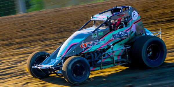 A colorful sprint car racing on a dirt track.