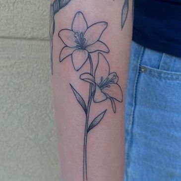 Minimalistic black ink tattoo of two lilies on the forearm.