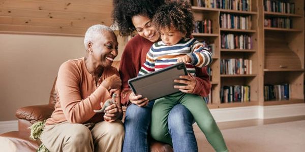 Three generations enjoying a tablet together on a couch.