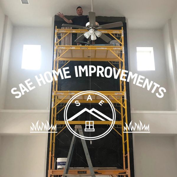 Man working on high scaffolding inside a home with SAE Home Improvements logo.