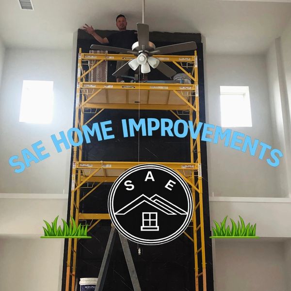 Worker on scaffolding inside a home with SAE Home Improvements branding.