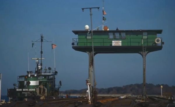 A green vessel named Mari Beth Andrie docked beside a raised green structure.