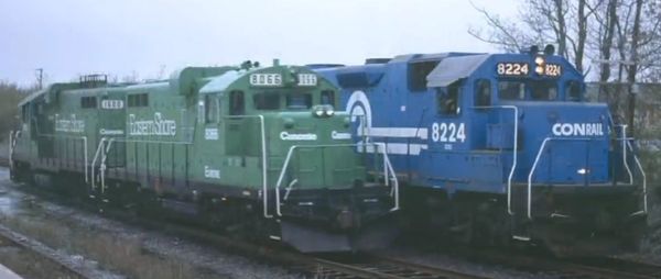 Two Conrail diesel locomotives, one green and one blue, on parallel tracks.