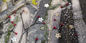 Close-up of fabric with intricate embroidery and star-shaped sequins.