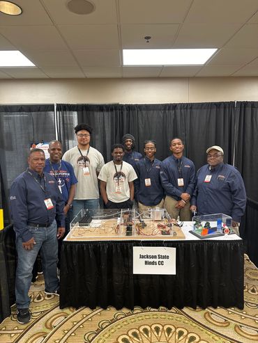 A group of men posing behind a robotics project at a science fair.