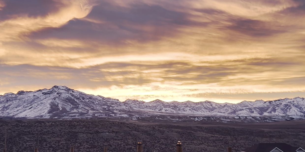 Snow-covered mountains under a dramatic sunset sky.