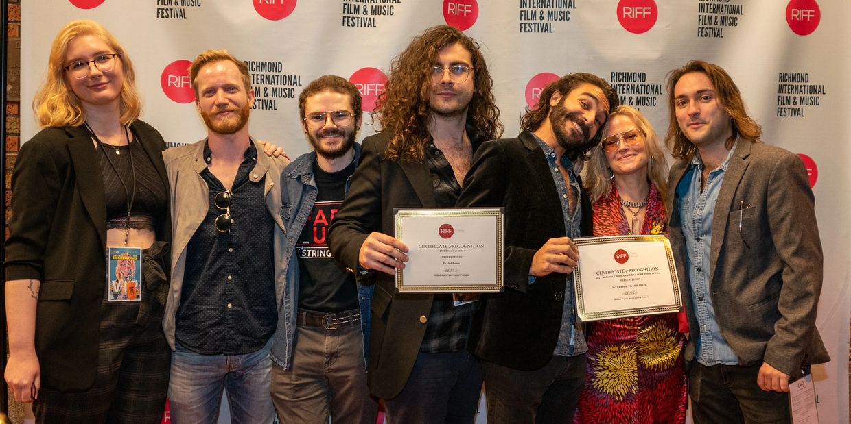 Group of seven people holding recognition certificates at Richmond International Film &amp; Music Festival.