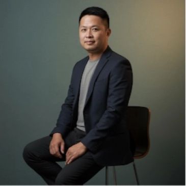 一位穿着休闲西装的男子坐在椅子上。