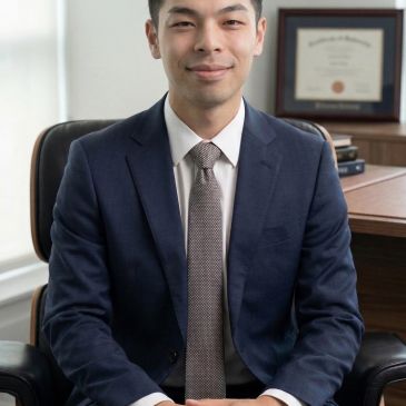 穿着西装的年轻男子微笑坐在椅子上。