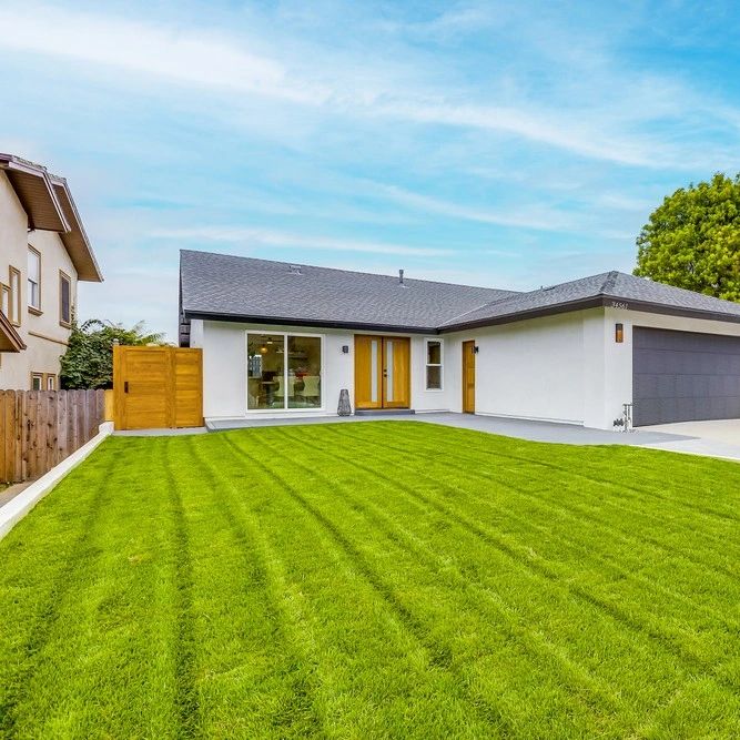 Modern single-story house with a large green lawn and wooden accents.