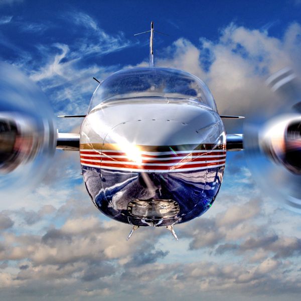 Twin engine airplane flying through the clouds with a brilliant shine