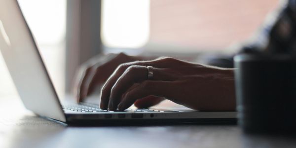 Hands typing on a laptop keyboard in soft natural light.