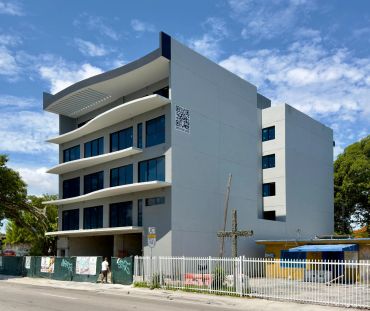 Modern white building with large windows under blue sky.