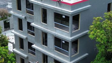 A concrete building under construction with window openings.