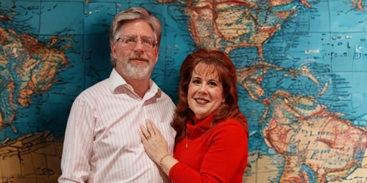 Couple posing in front of a world map.