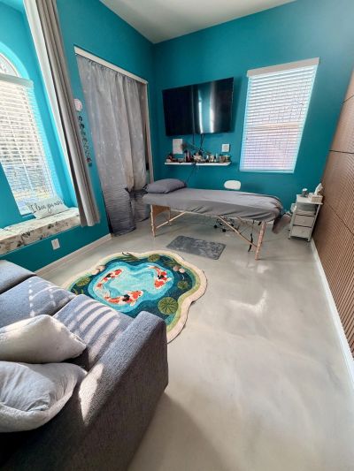 Bright therapy or massage room with teal walls and koi fish rug.