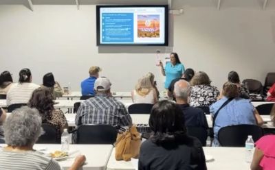 Instructor giving a presentation to a seated audience in a classroom.